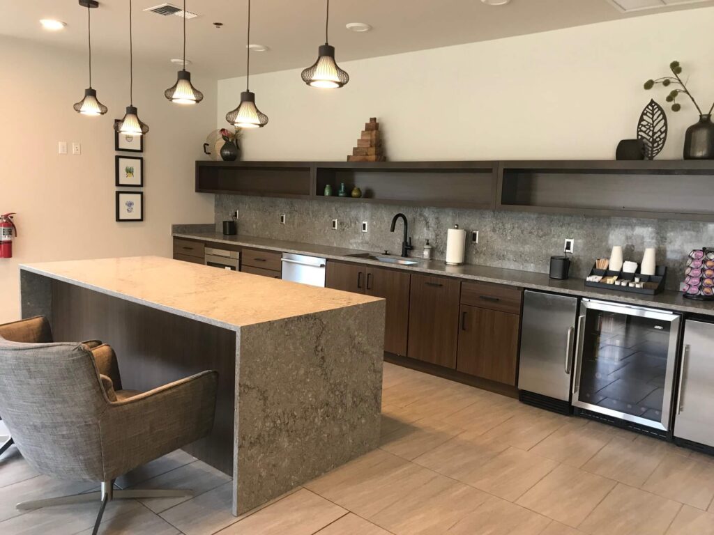 A kitchenette in busy gray quartz with full-height backsplash and waterfall edges on the island.